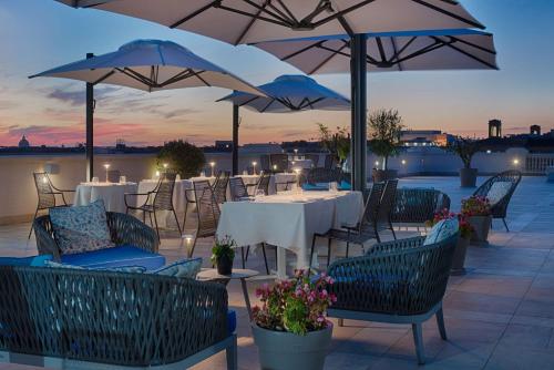 a patio with tables and chairs and umbrellas at NH Collection Palazzo Cinquecento in Rome