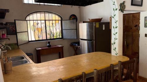 a kitchen with a large wooden table and a refrigerator at Botanical Studios Sayulita in Sayulita