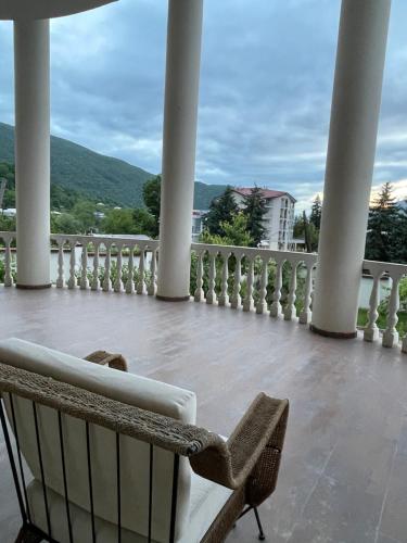 a porch with a bench and a view of the mountains at Villa Baqs in Racha in Ambrolauri