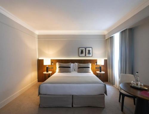 a bedroom with a large white bed and a table at Hotel Noble Haven Unit OF Lacasa Near Airport in New Delhi