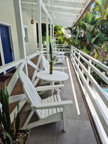 un portico con sedie bianche, tavolo e pianta di Lizard King Hotel & Suites a Puerto Viejo
