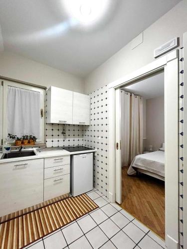 a kitchen with white cabinets and a bed in a room at La Dimoraga in Chiubbica