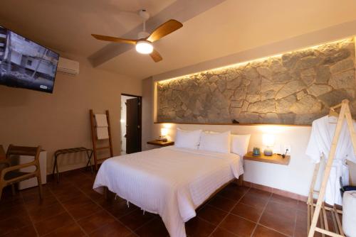 a bedroom with a bed and a rock wall at La Posada Hotel Boutique in Manzanillo