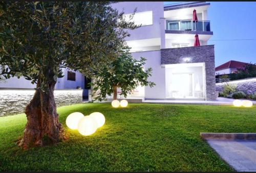 a house with lights in the grass next to a tree at Apartments Maritea in Vodice