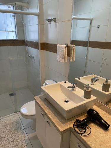 a bathroom with a sink and a toilet and a mirror at Apto no centro da cidade mais alemã do Brasil in Pomerode