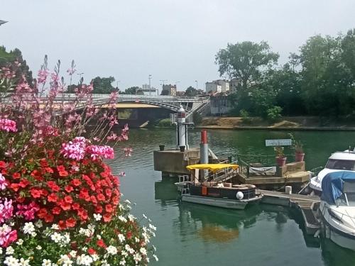 a boat is docked in a river with flowers at Escapade entre Ville et Rivière in Nogent-sur-Marne