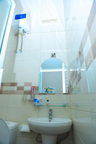 a bathroom with a sink and a mirror and a toilet at Rostel Villa Hotel in Mbeya