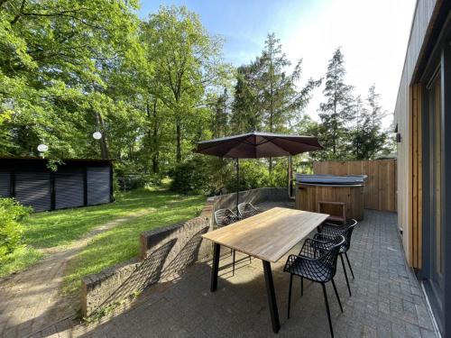 a wooden table with an umbrella on a patio at Tranquil holiday home in the middle of nature in Zelhem