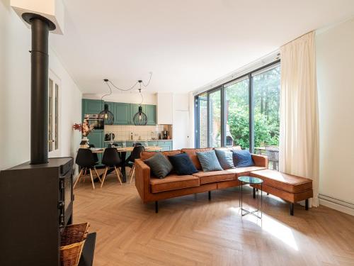 a living room with a brown couch and a kitchen at Tranquil holiday home in the middle of nature in Zelhem