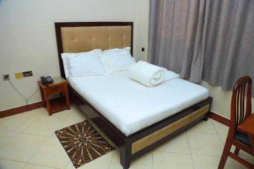 a bed with white sheets and pillows in a room at Rostel Villa Hotel in Mbeya