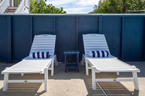 two white chairs sitting next to a blue wall at Salty Breeze - Walk to Beach - Pool - Hot Tub - EV in Duck