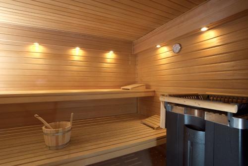 a sauna with a clock and a bucket in it at Das Windhuk in Westerland (Sylt)