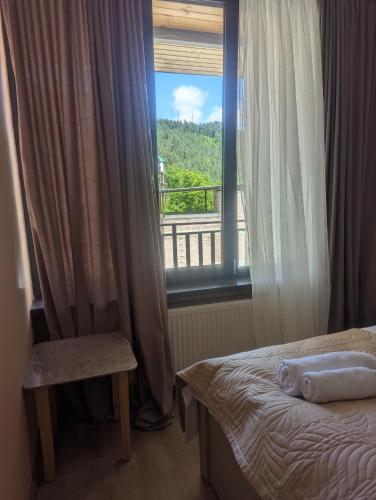 a bedroom with a bed and a window and a chair at OR-Ni in Borjomi