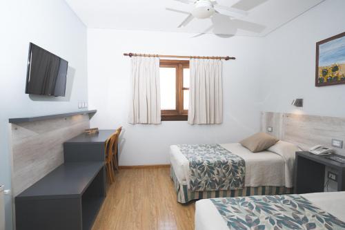 a room with two beds and a desk and a window at Hotel Bahia Nueva in Puerto Madryn