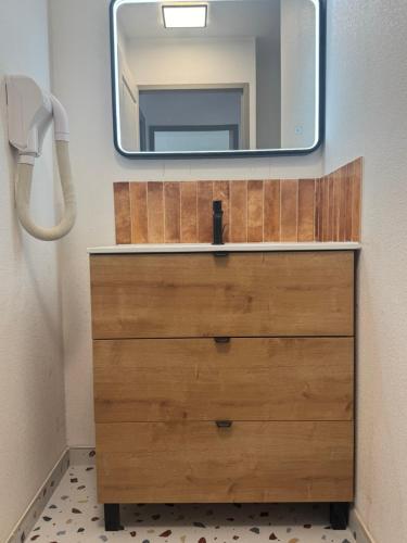 - une commode avec un miroir au-dessus dans l'établissement Maison Vacances au Domaine de Golf Piscine, à Fabrègues