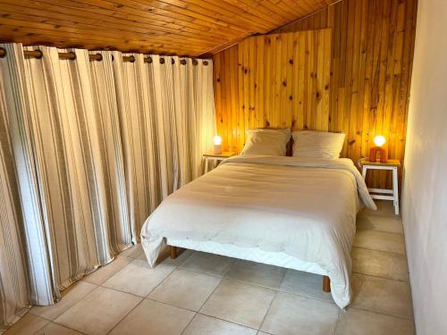 una camera da letto con un letto in una stanza con pareti in legno di Ideal house for family vacations, peaceful setting a Lège-Cap-Ferret