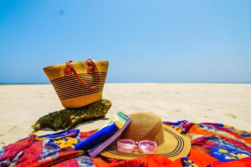 a straw hat and sunglasses on a blanket on the beach at YU Resort in Msambweni