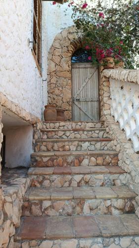 a stone building with a door and stairs with flowers at Rustic-style apartment in LMP