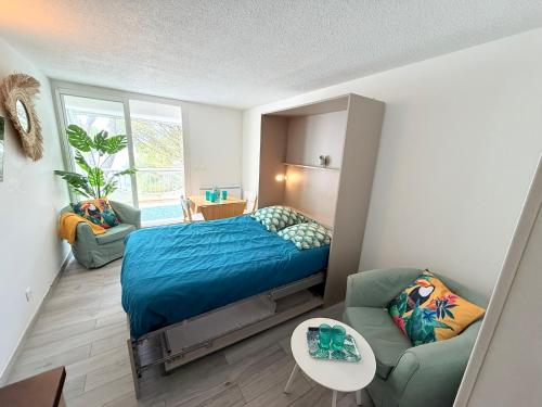 a bedroom with a bed and a couch and a window at Studio 4pers La Grande Motte Ponant, Vue exceptionnelle lac, double terrasse, Parking, base nautique, golf & plage à pied, draps & serviettes fournis in La Grande-Motte