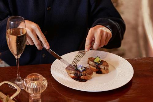 a person cutting a plate of food with a knife and fork at Sheraton Hanoi Hotel in Hanoi