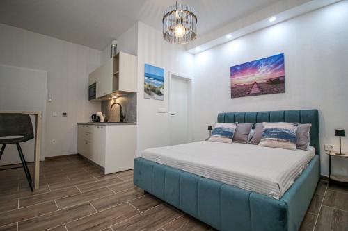 a bedroom with a blue bed and a kitchen at Apartman Lamanova in Rovinj