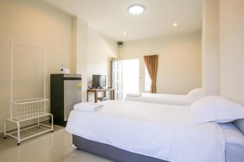 a bedroom with two beds and a refrigerator at J-House Phetchaburi in Phetchaburi