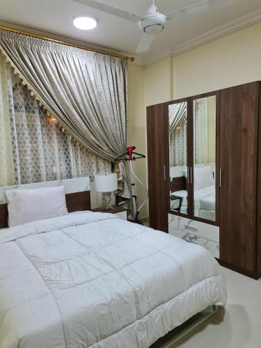 a bedroom with a large white bed and a mirror at العربي للشقق المفروشة in Salalah