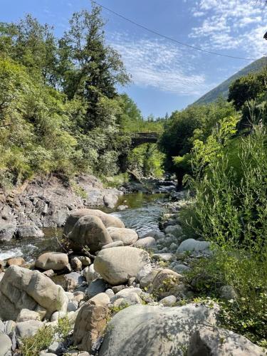 a river with rocks and a bridge in the background at Basilico Apartment with stunnung views in Scogna Superiore