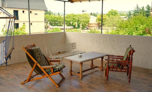 a patio with two chairs and a table and a bench at Pospolita Guest House in Kutaisi