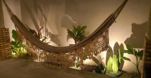 a rattan hammock sitting next to some plants at Pousada Viva Praia in Paracuru