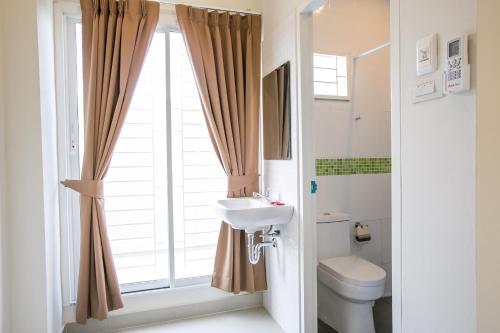 ペッチャブリーにあるJ-House Phetchaburiのバスルーム(洗面台、トイレ付)、窓が備わります。