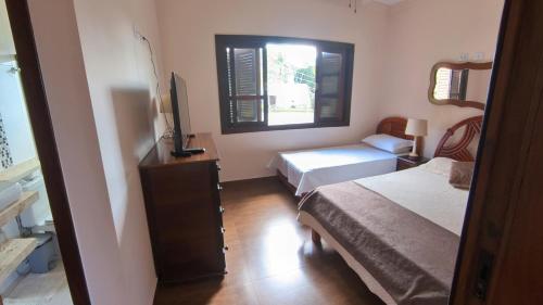 a small bedroom with two beds and a window at Casa Centro de Guararema - Casa Bela Vista in Guararema