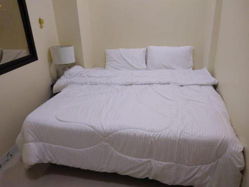 a white bed with white sheets and pillows at العربي للشقق المفروشة in Salalah