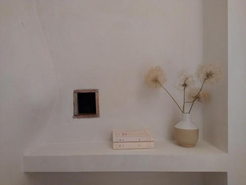 a white shelf with a vase and flowers on it at Maison La Petite Cour - Spa in Visan