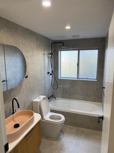 a bathroom with a toilet and a tub and a sink at Coogee Treehouse in Sydney