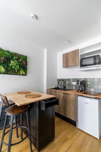 - une cuisine avec un comptoir en bois et une table dans l'établissement le cocon du peyrou, à Montpellier