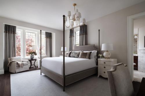 a bedroom with a canopy bed and a chair at 86 State Circle - Luxury Boutique Hotel in Annapolis