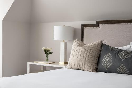 a bedroom with a bed with a lamp and pillows at 86 State Circle - Luxury Boutique Hotel in Annapolis