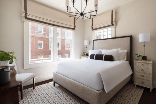 a bedroom with a large white bed and a chandelier at 86 State Circle - Luxury Boutique Hotel in Annapolis