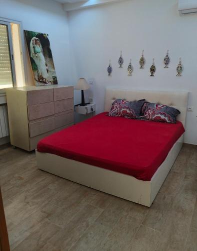 a bedroom with a large bed with a red blanket at Appartement RanYara vue piscine et détentee Hamamet in Nabeul