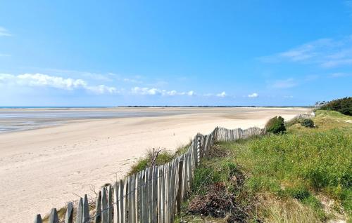 a sandy beach with a wooden fence and the ocean at Amazing Home In Creances With Wifi in Créances
