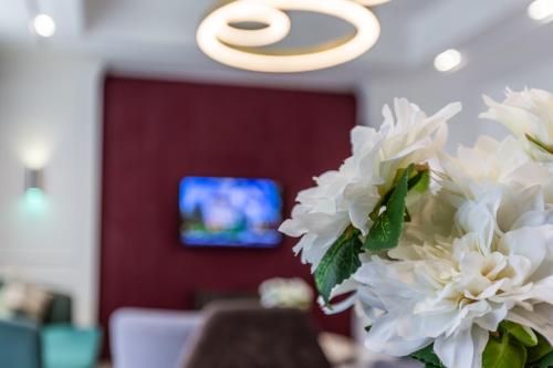 a vase of white flowers in a room with a tv at Ivy Garden Hotel Baku in Baku