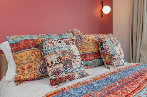 a bed with four pillows and a blanket on it at LUTON LUXURY LIVING, Large PREMIUM House, Beautifully Landscaped PRIVATE GARDEN, Newly Refurbished Throughout, PARKING FOR 2 VEHICLES, Great Access to Central Luton & the M1 Motorway in Luton