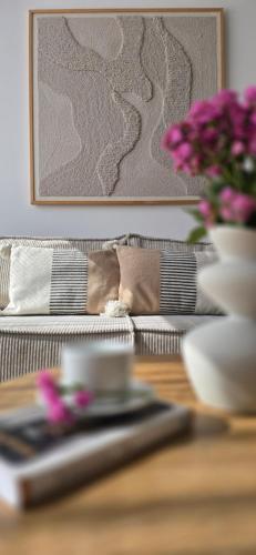 a table with a plate and a vase with flowers on it at Apartament Gdańska in Gdańsk