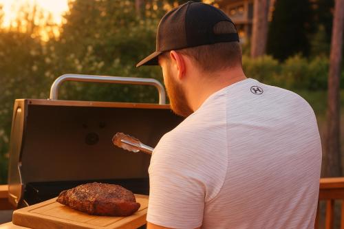 a man is cooking a steak on a grill at Sunset Mountain Hot Tub, Fire Table, Epic Views in Shaver Lake