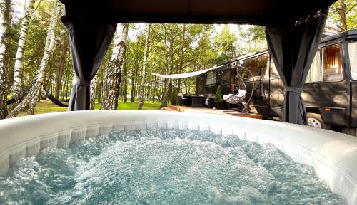 a hot tub in a camper with a van at DOM LAS BUS twój leśny azyl z prywatnym jacuzzi 