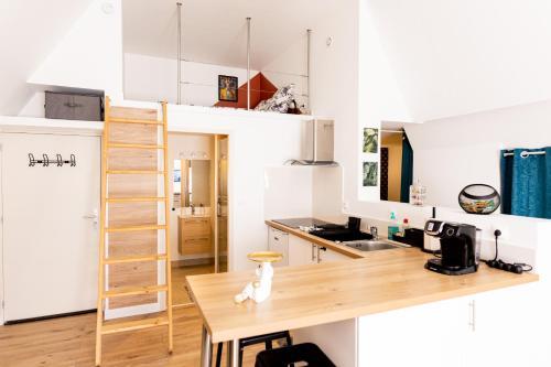 Elle comprend une petite cuisine avec des placards blancs et une table en bois. dans l'établissement Mirabeau Sous Les Toits - Tours, à Tours