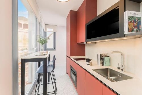 a kitchen with red cabinets and a sink and a bar stool at Picasso III in Málaga