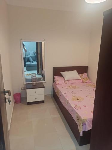 a small bedroom with a bed and a mirror at بورتو الجولف in Dawwār Abū Maḩrūs