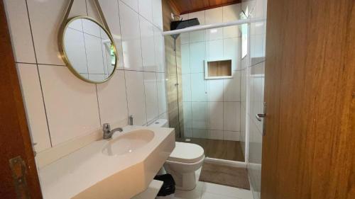 a bathroom with a sink and a toilet and a mirror at Encanto do Mar in Praia de Araçatiba